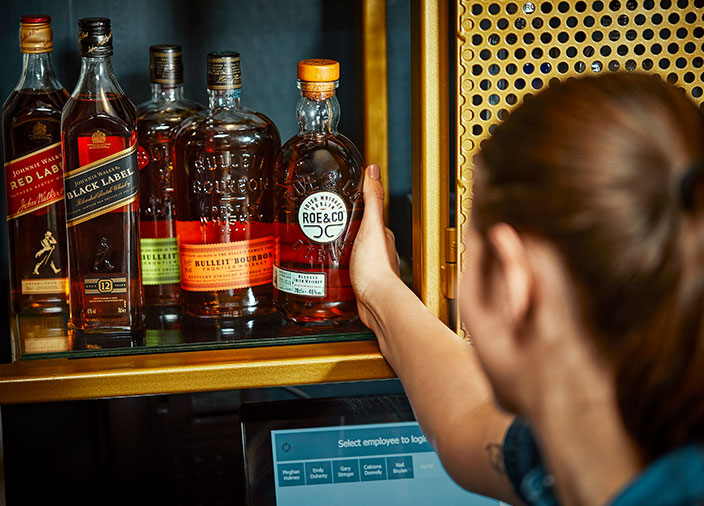 Barstaff lifting a bottle of Roe and Co from the backbar 