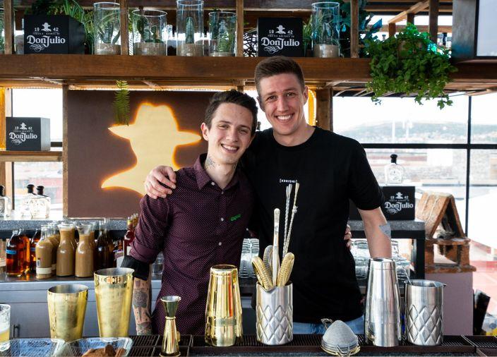 male bartenders behind bar smiling