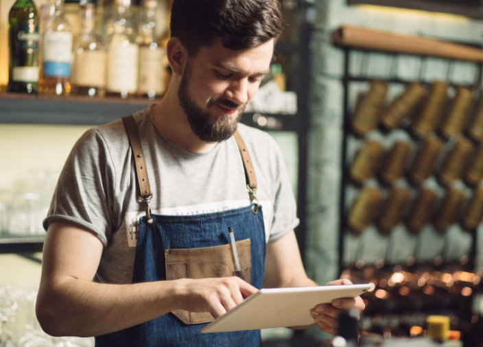 Man looking at an iPad in front of a back bar