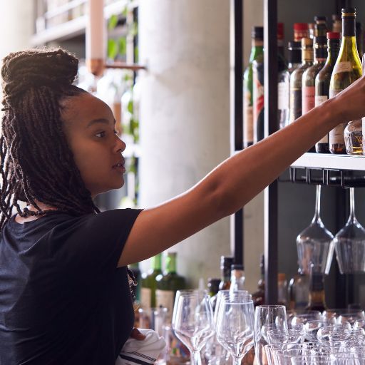Personal del bar levantando una botella de un estante