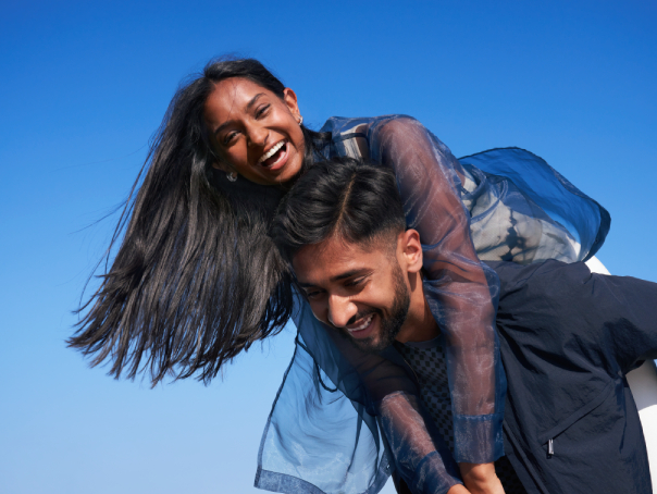 una donna dai lunghi capelli scuri sorride e abbraccia un uomo sorridente