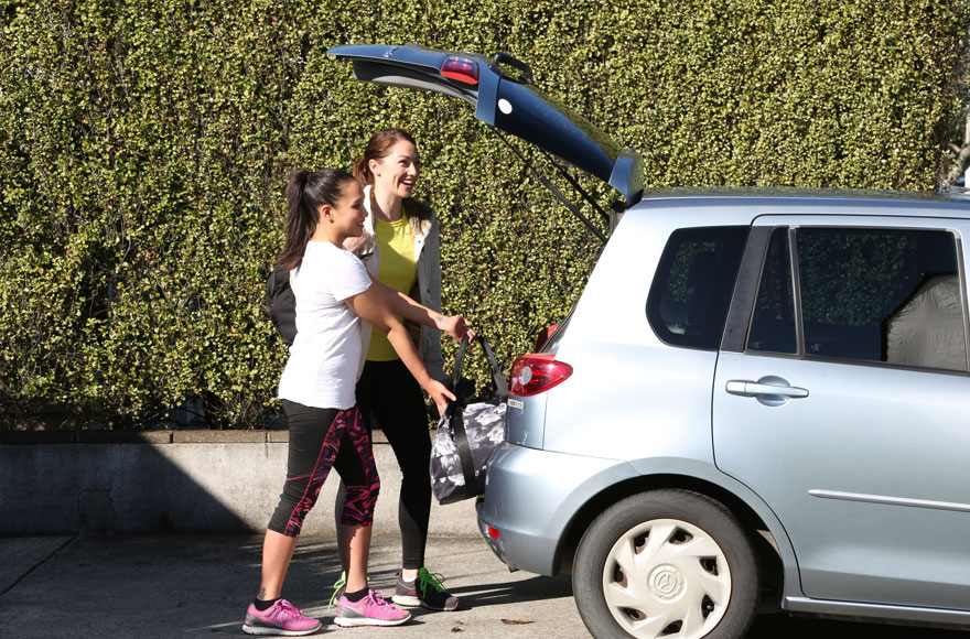 Women putting a bag into the boot of a car.