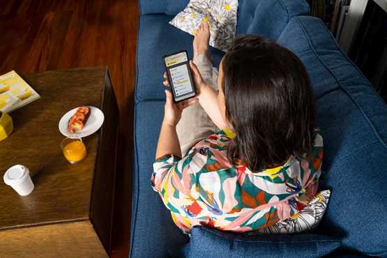 Woman sits on couch researching insurance on her phone