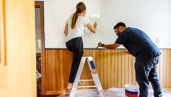 A couple painting a room in their home.