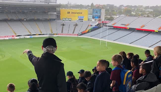 person in the bleachers pointing down to the field at Eden Park