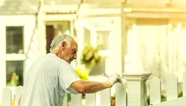 older man painting fence
