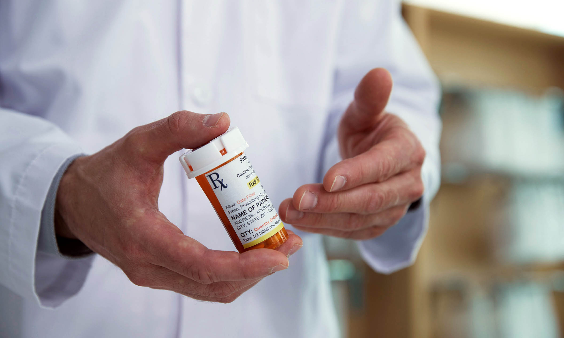 A pharmacist holding a prescription bottle explaining the label