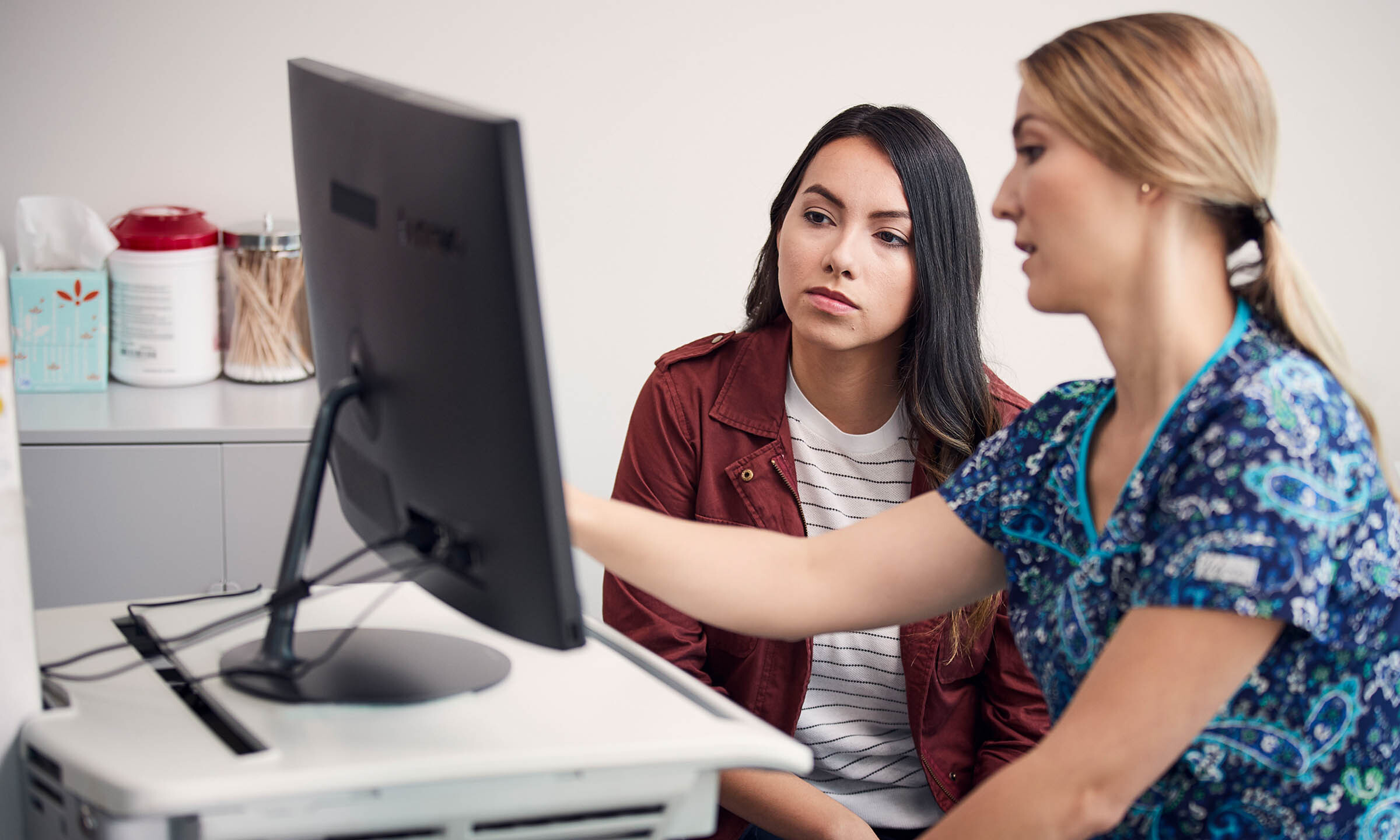 Nurse talking to patient in front of computer