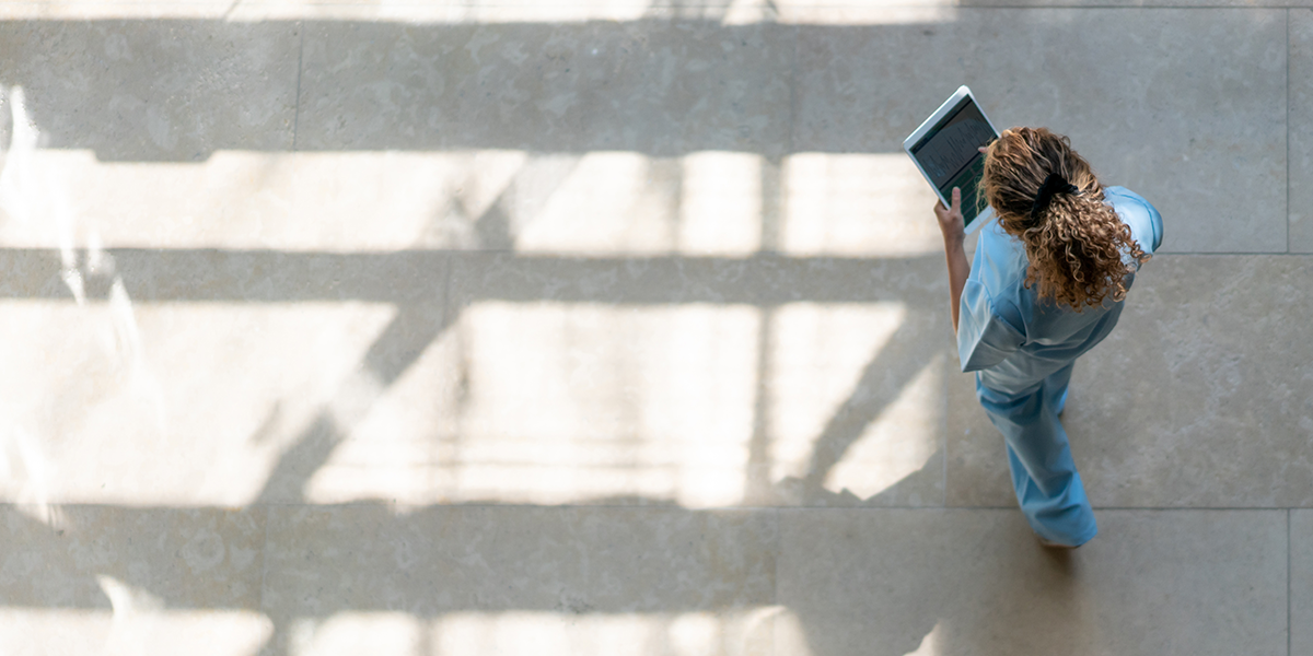 A nurse walking down the hall while looking at her iPad