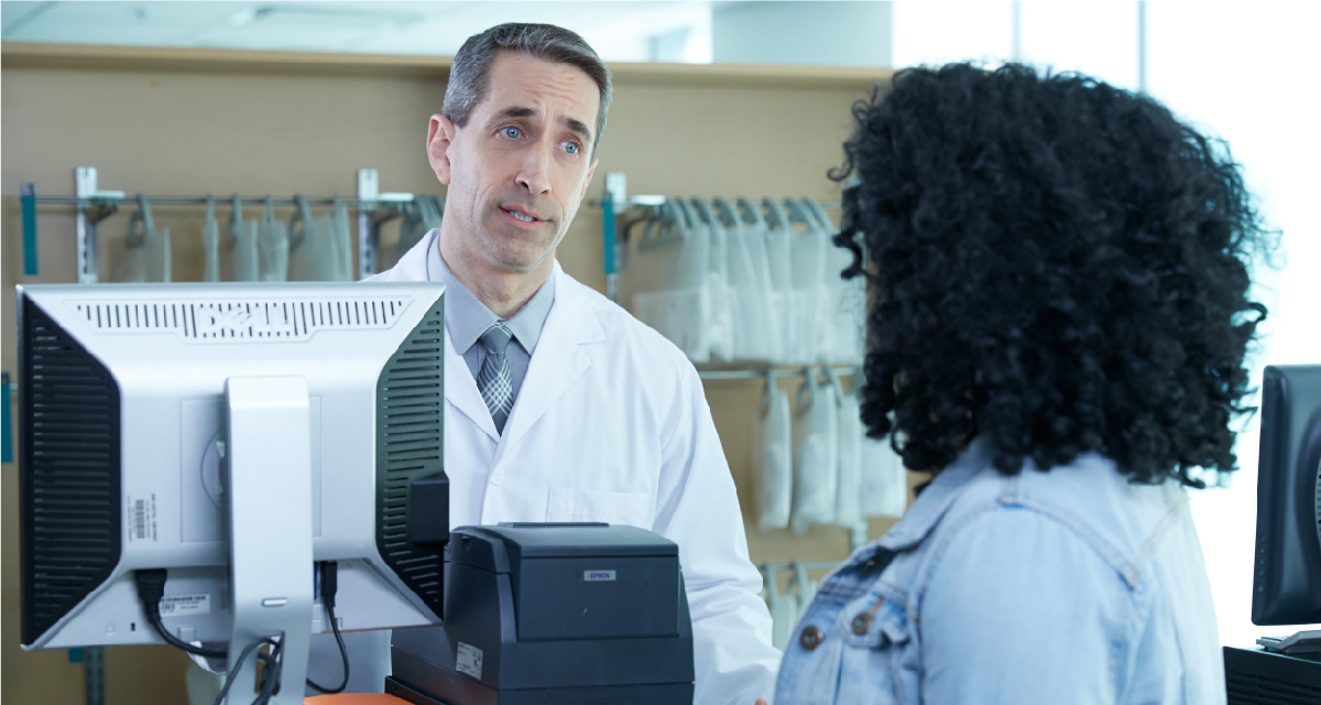 A patient speaks with a pharmacist at the counter
