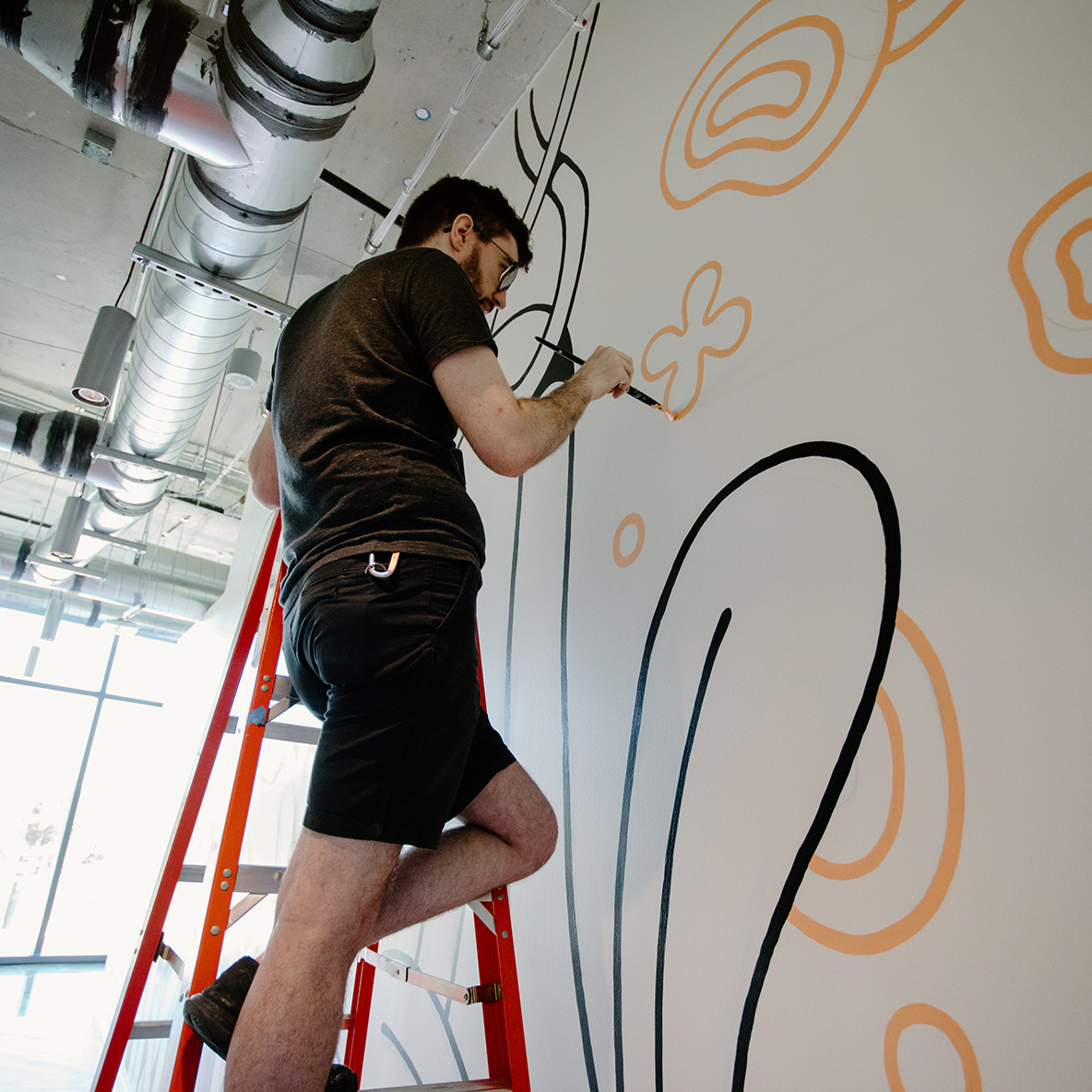 A collage of photos showing local artists painting murals inside CoverMyMeds' campus. 