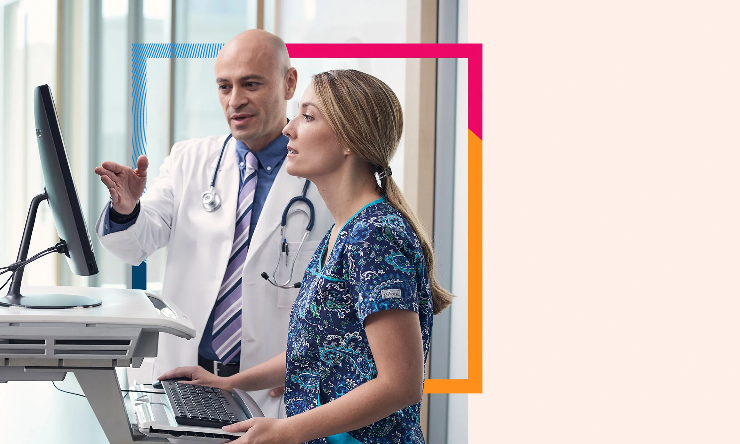 Physician and nurse discuss patient therapies at a movable patient kiosk.