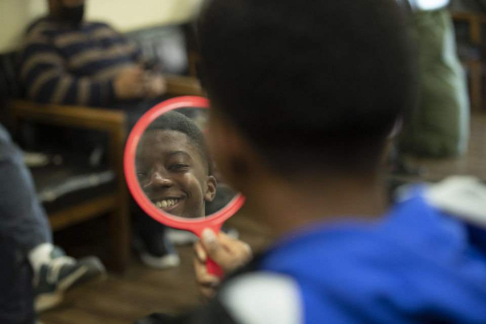 Tonia's son looks into a mirror at the barber shop