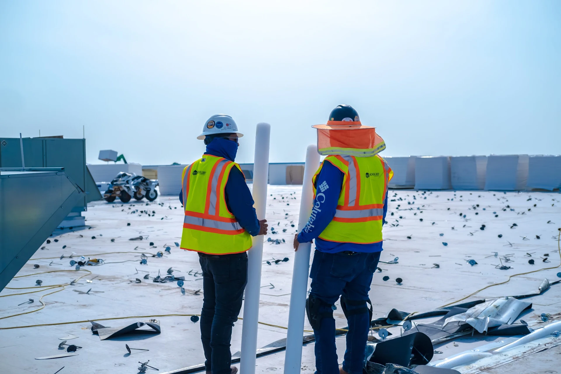 Two men in hazard vests standing on a roof