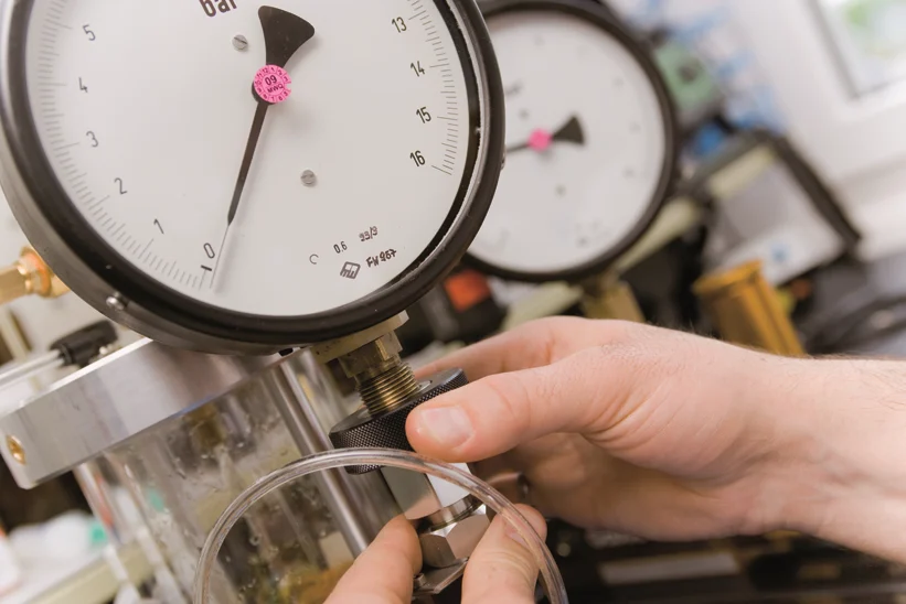 A hand tightening a valve on a gas gage