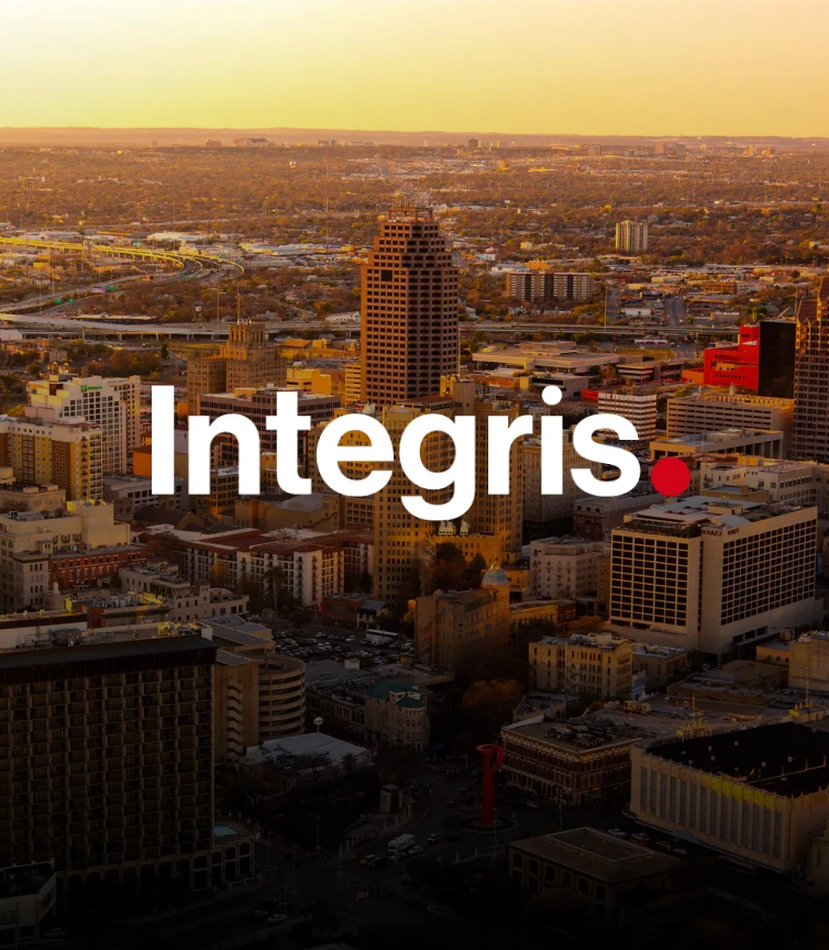 Integris logo over a birds eye view of a city at sunset