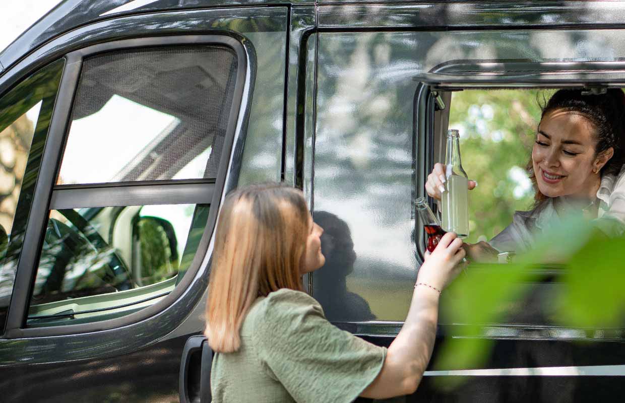 Two women drinking a drink in the caravan