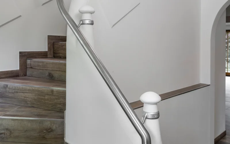ein Treppenaufgang mit dunklen Holzstufen und silbernem Geländer