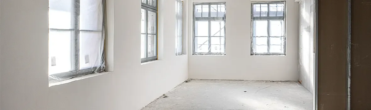 leerer Wohnraum in der Sanierung mit weißen Wänden und Folie an den Fenstern