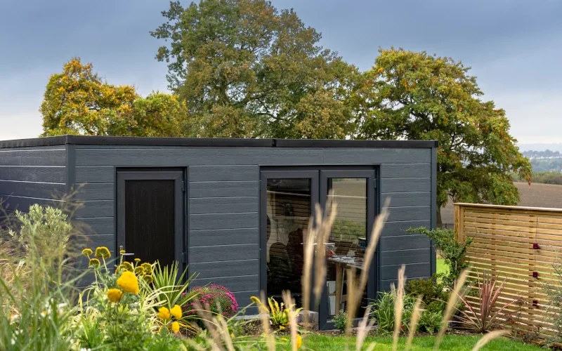 kleines Haus im Garten mit schwarzen Fassadenplatten