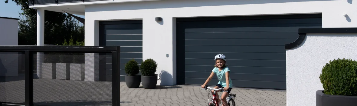 Hausgrundstück mit smarten Garagen- und Einfahrtstoren und einem Mädchen auf dem Fahrrad