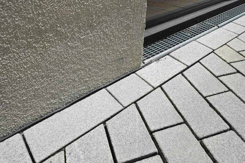 Hauswand mit Trennschutzlage und gepflasterter Fläche 