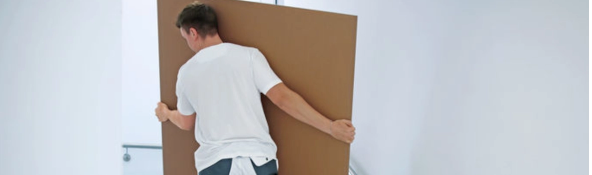 Junger Handwerker trägt die Schallschutzplatte Silentboard 2in1 der Firma Knauf die Treppe hinauf.