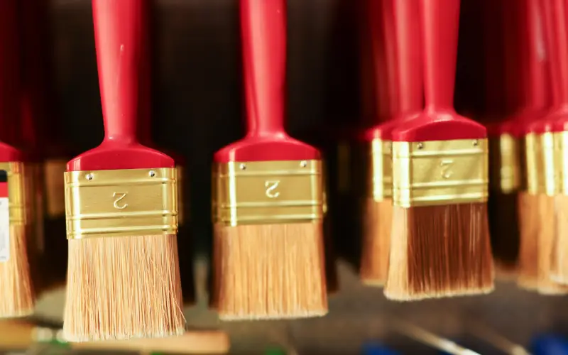 Mehrere rote Pinsel mit goldenen Metallhülsen hängen nebeneinander.