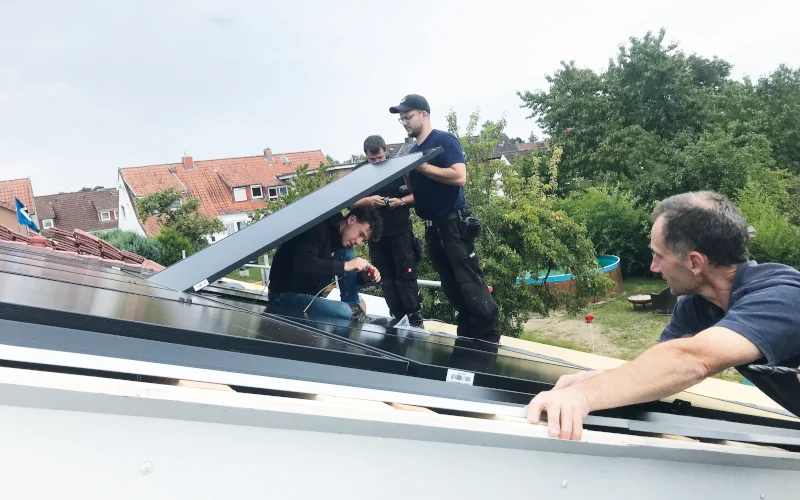 Arbeiter bringen Solarpaneele am Schrägdach an 
