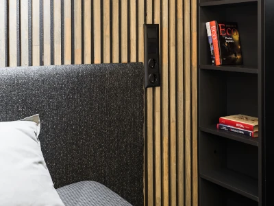Hinter einem schwarzen Bett sind Akustikpaneele an der Wand befestigt