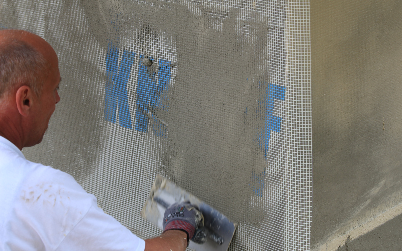 Handwerker verputzt Fassade mit Armierungsgewebe von Knauf