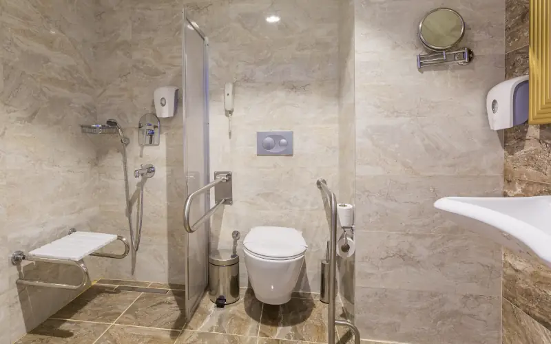Barrierefreies Badezimmer mit Duschsitz und Haltegriffen.
