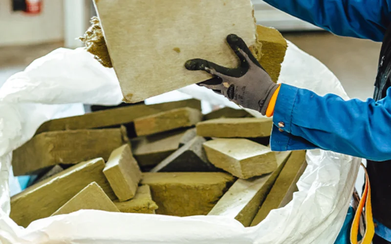 Handwerker mit Stücken Dämmstoff in der Hand