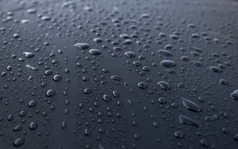 Wassertropfen auf schwarzer glatter Oberfläche