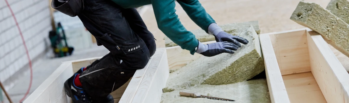 Handwerker drückt Dämmplatten in Holzkonstruktion 