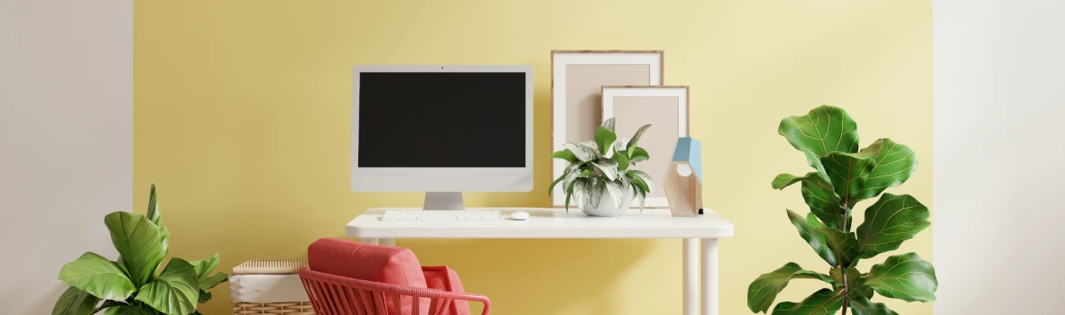 weiße Wand mit gelbem Muster und einem Schreibtisch mit Deko und Pflanzen 