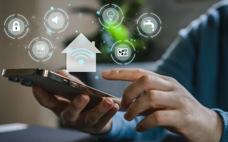 menschliche Hand mit Smartphone in der Hand und Symbolen für SmartHome darüber