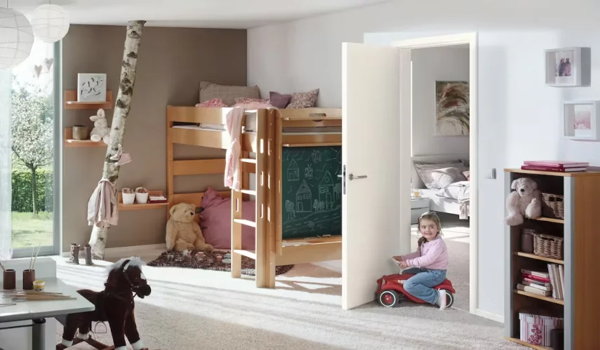 ein kleines Mädchen fährt auf einem Auto ins Kinderzimmer hinein 