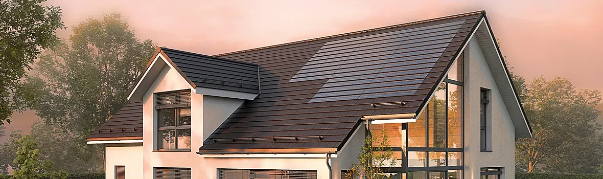 Helles Haus mit dunklen Dachsteinen und Photovoltaikanlage auf dem Dach. 
