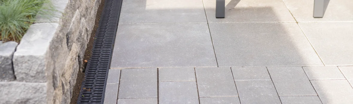 Entwässerungsrinne von ACO auf einer Terrasse an einer Steinmauer liegend