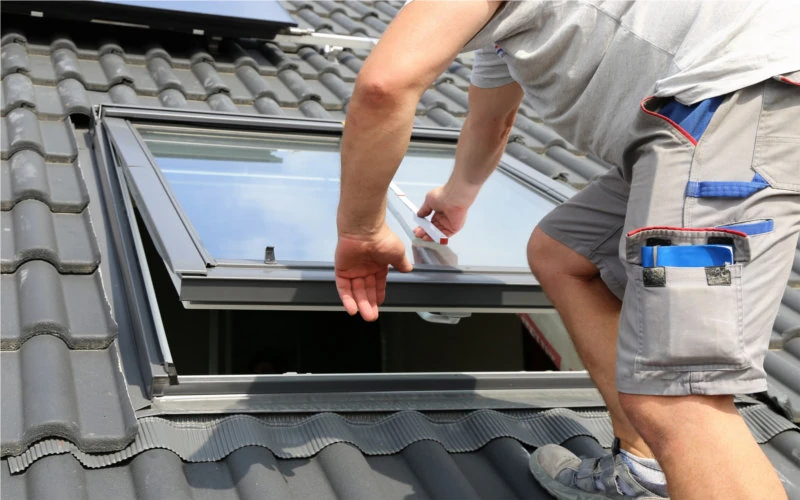 Handwerker prüft ein eingebautes Dachfenster auf dem Dach