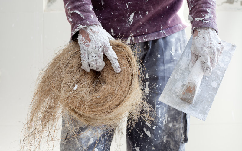 Mann hält Hanfbaustoff und eine Kelle in der Hand