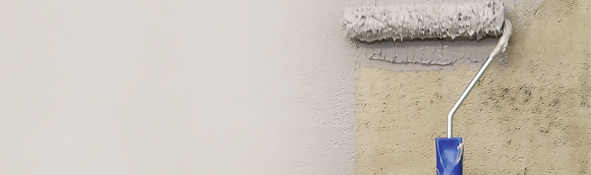 vergilbte Wand wird mit Farbrolle weiß angestrichen 