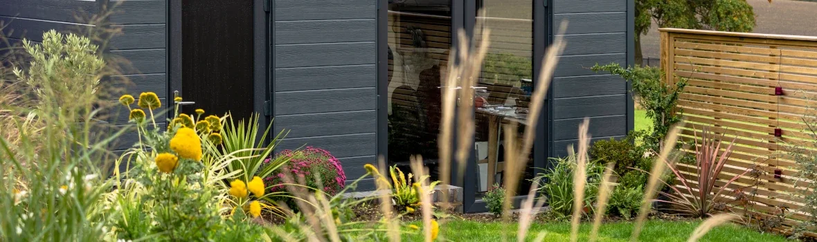 kleines Haus im Garten mit schwarzen Fassadenplatten