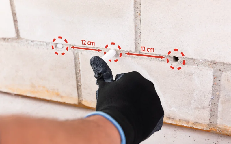Handwerker drückt Horizontalsperren-Sticks von redstone in eine Außenwand