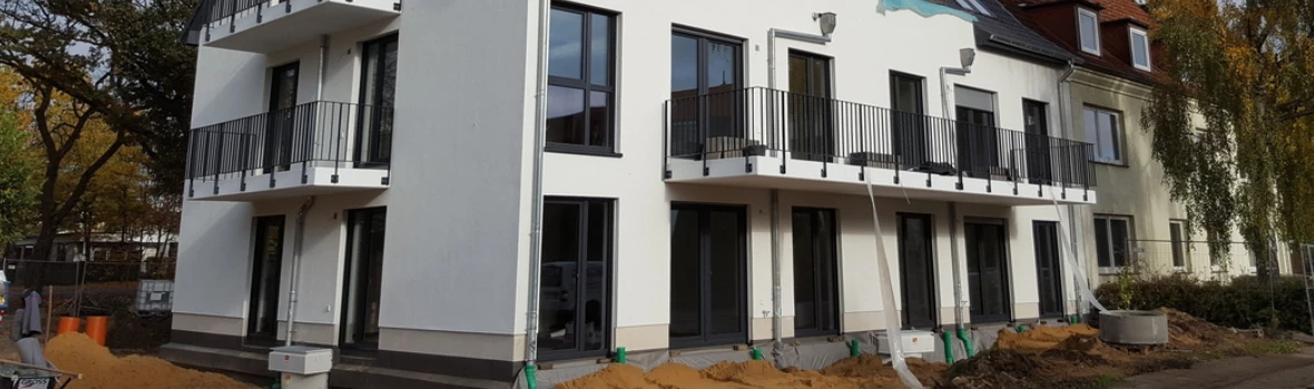 Ein Wohngebäude mit weißer Fassade, Fenster und Balkons.