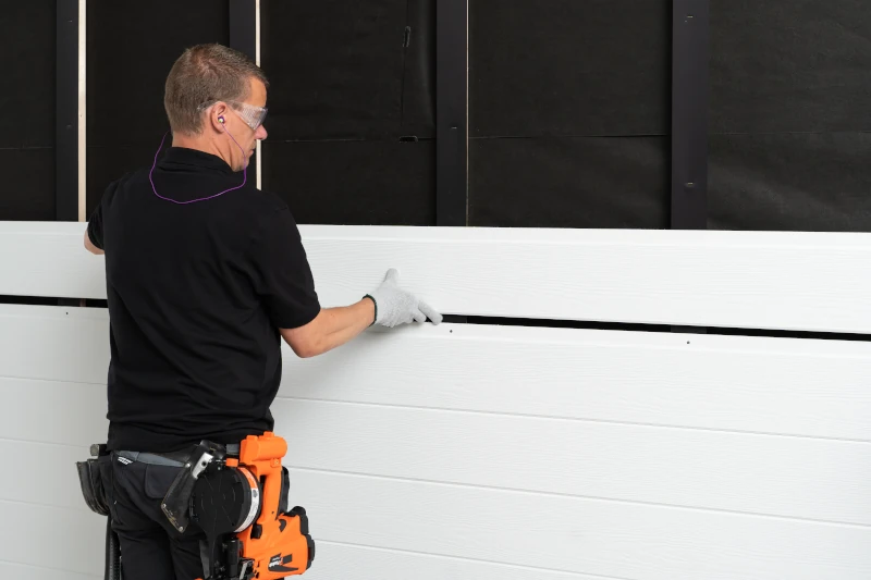 Handwerker bringt Fassadenplatten an Konstruktion am Haus an