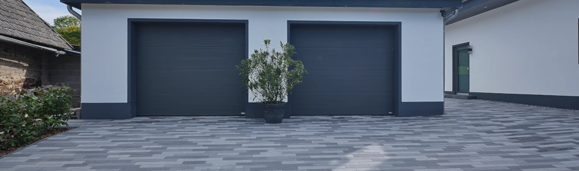 Einfahrt mit Doppelgarage mit anthrazitfarbene Garagentoren 