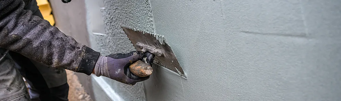 Reaktivabdichtung mit einem Spachtel auf einer Hauswand aufgetragen