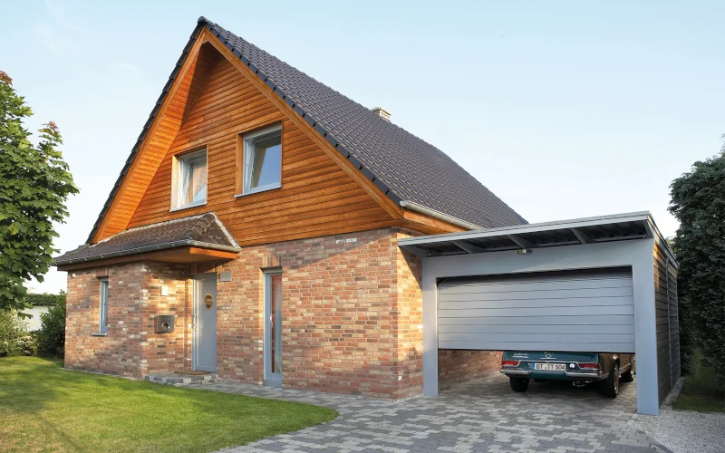 großes Wohnhaus mit Garage mit grauen, leicht geöffnetem Tor und Auto darin